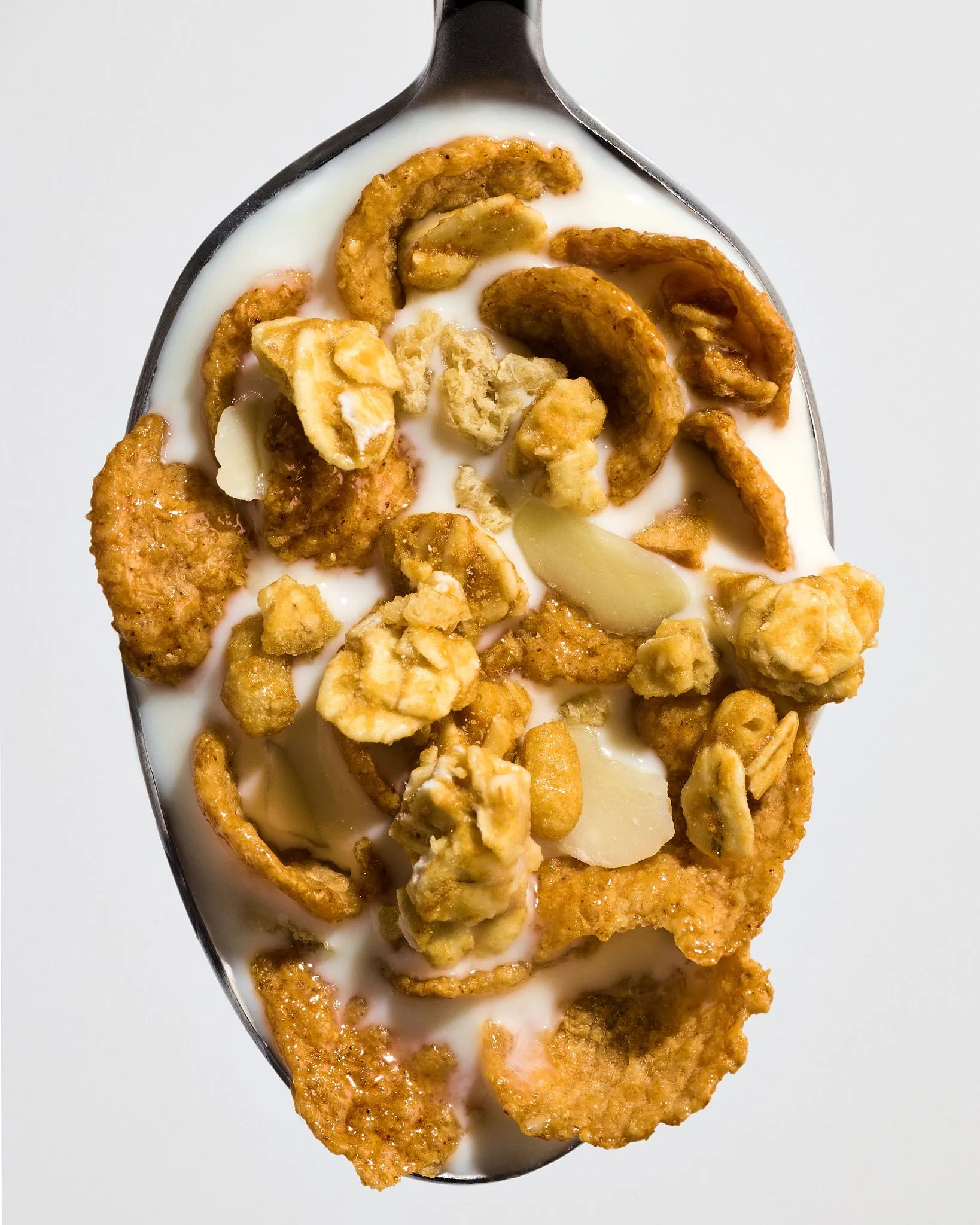 Overhead close-up of a spoonful of cereal with milk.