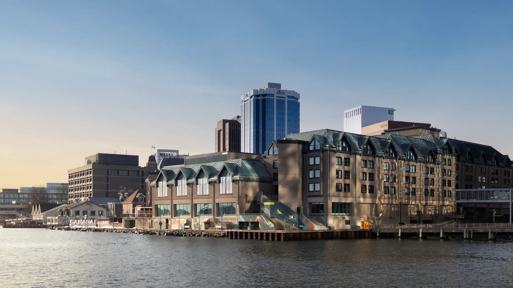 City skyline on the waterfront with varied architectural styles under a clear blue sky.
